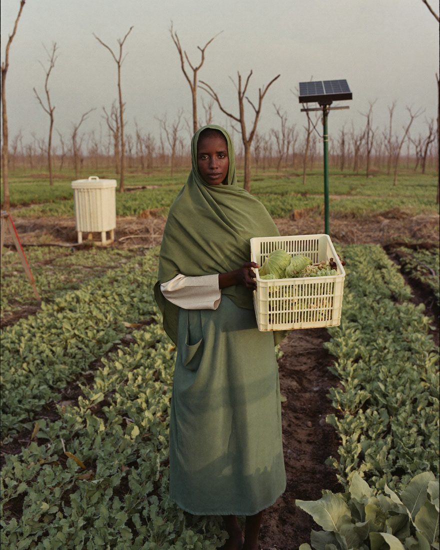 A Somali woman works a climate-smart irrigated plot beside a water storage tank in dry country.